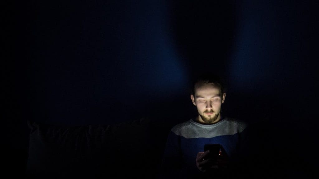 man looking at smartphone in the dark
